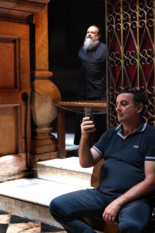 Mann blickt auf sein Mobiltelefon in der Kirche